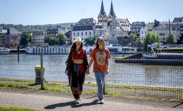 Freed Russian artist Sasha Skochilenko, left, and her partner, Sofya Subbotina, walk at the banks of the Mosel River in Koblenz, Germany, Saturday, Aug. 10, 2024. (AP Photo/Michael Probst)