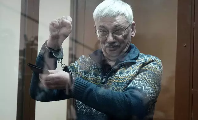 FILE - The co-chair of the Nobel Peace Prize winning Memorial Human Rights Centre Oleg Orlov gestures standing in a glass cage after he was taken into custody in the courtroom during court session for a new trial on charges of repeated discrediting Russian military, in Moscow, Russia, on Tuesday, Feb. 27, 2024. Orlov, a veteran human rights campaigner, was convicted of publicly discrediting the Russian military and sentenced to 2½ years in prison in 2024. He has rejected the charges as politically motivated. (AP Photo/Alexander Zemlianichenko, File)