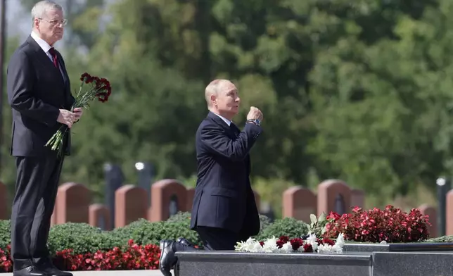 Russian President Vladimir Putin, right, and Representative of Russian President in the North Caucasus Federal District Yuri Chaika, attend a ceremony to lay flowers at the City of Angels cemetery, where the victims of the 2004 Beslan school siege were buried, in Beslan, Republic of North Ossetia-Alania, Russia, Tuesday, Aug. 20, 2024. (Gavriil Grigorov, Sputnik, Kremlin Pool Photo via AP)