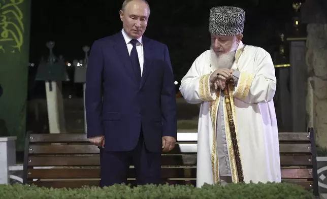 Russian President Vladimir Putin, left, and Akhmat Kadyrov's cousin, Chairman of the Council of Alims of the North Caucasus Federal District Khozh-Akhmed Kadyrov stand at the grave of the first president of Chechnya Akhmat-Khadzhi Kadyrov in the village of Akhmat-Yurt, Chechen Republic, Russia, Tuesday, Aug. 20, 2024. (Vyacheslav Prokofyev, Sputnik, Kremlin Pool Photo via AP)