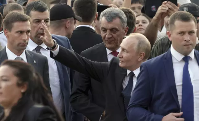 Russian President Vladimir Putin waves to local residents as he walks in Vladikavkaz, Republic of North Ossetia-Alania, Russia, Tuesday, Aug. 20, 2024. (Gavriil Grigorov, Sputnik, Kremlin Pool Photo via AP)