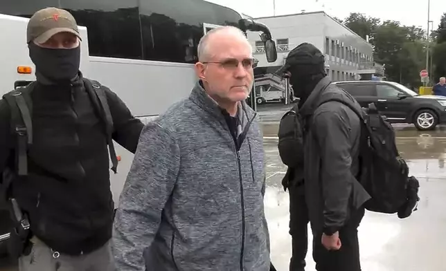 In this image made from video provided by Russian Federal Security Service via RTR on Thursday, Aug. 1, 2024, Paul Whelan, center, a former U.S. Marine who was arrested on espionage charges, is escorted by Russian Federal Security Service agents, left, as they arrive at an airport outside Moscow, Russia. (Russian Federal Security Service/RTR via AP)