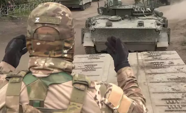 This photo taken from video released by Russian Defense Ministry press service on Monday, Aug. 12, 2024, shows Russian military vehicle boarding a lowboy for transfer to Kursk region. (Russian Defense Press Service via AP)