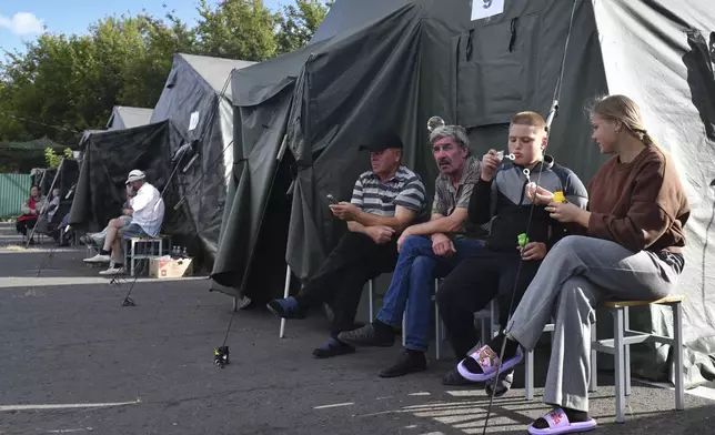 People evacuated from a fighting between Russian and Ukrainian forces in Kursk region sit next to tents at a temporary residence center in Kursk, Russia, Monday, Aug. 12, 2024. (AP Photo)