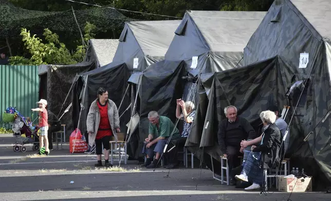 People evacuated from a fighting between Russian and Ukrainian forces in Kursk region sit next to tents at a temporary residence center in Kursk, Russia, Monday, Aug. 12, 2024. (AP Photo)