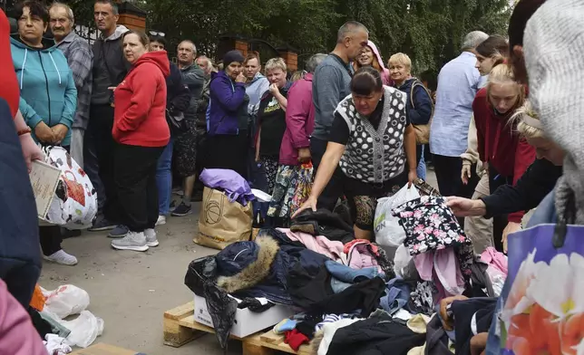 People evacuated from fighting between Russian and Ukrainian forces queue to receive humanitarian aid at a distribution center in Kursk, Russia, Monday, Aug. 12, 2024. (AP Photo)