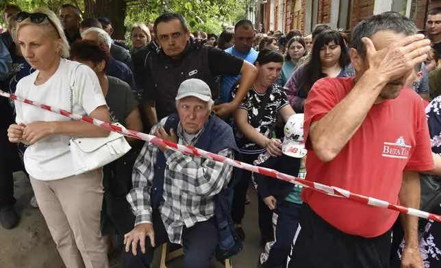 People evacuated from a fighting between Russian and Ukrainian forces queue to receive humanitarian aid at a distribution center in Kursk, Russia, Monday, Aug. 12, 2024. (AP Photo)