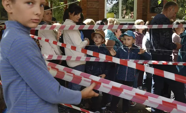 People evacuated from fighting between Russian and Ukrainian forces queue to receive humanitarian aid at a distribution center in Kursk, Russia, Monday, Aug. 12, 2024. (AP Photo)