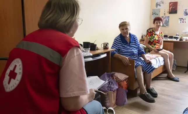 A Russian Red Cross worker, back to a camera, listens to people evacuated from a fighting between Russian and Ukrainian forces in Kursk region, at a temporary residence center in Kursk, Russia, Sunday, Aug. 11, 2024. (AP Photo)