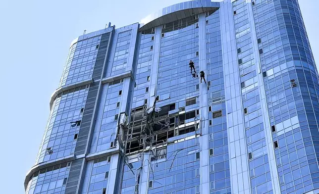 This photo released by the governor of the Saratov region, Roman Busargin, in his official Telegram channel on Monday, Aug. 26, 2024, shows municipal employees working at the side of a damaged building after a drone attack on the city of Saratov, Russia. (Saratov region governor Roman Busargin official Telegram channel via AP)