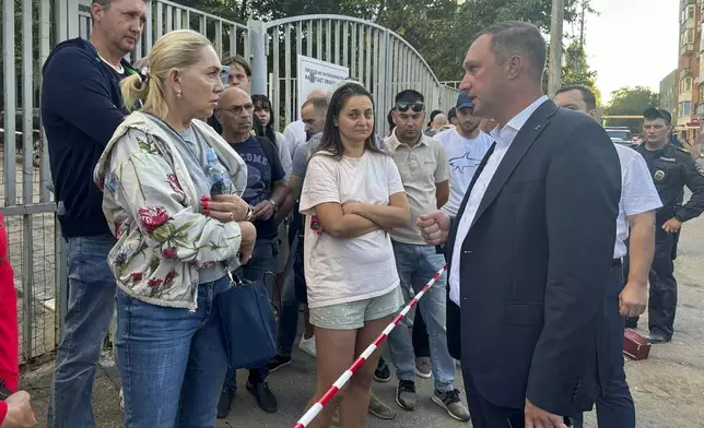 In this photo released by the governor of the Saratov region, Roman Busargin, in his official Telegram channel on Monday, Aug. 26, 2024, governor of the Saratov region Roman Busargin, right, speaks with residents of the building damaged by a drone attack on the city of Saratov, Russia. (Saratov region governor Roman Busargin official Telegram channel via AP)