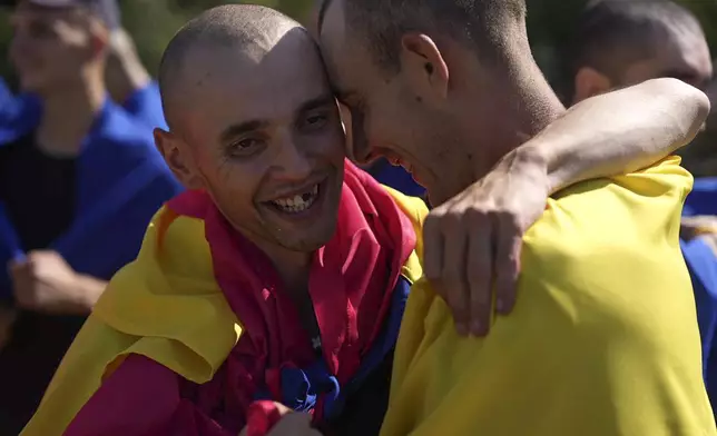 In this photo provided by the Ukrainian Presidential Press Office on Saturday, Aug. 24, 2024, Ukrainian prisoners of war wrapped in national flags hug each other after a prisoners exchange at an undisclosed location in Ukraine. (Ukrainian Presidential Press Office via AP)