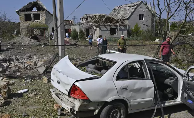 People walk in front of their damaged houses after Russian rocket attack in Usatove village near Odesa, Ukraine, Monday, Aug. 26, 2024. (AP Photo/Michael Shtekel)