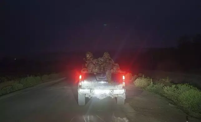 Ukrainian servicemen ride in a trunk of pickup truck towards their positions at the frontline in Donetsk region, Ukraine, on Wednesday, Aug. 21, 2024. (AP Photo/Evgeniy Maloletka)