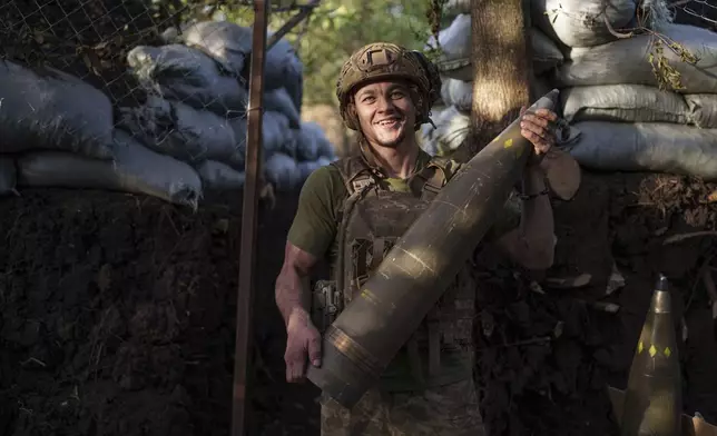 Ukrainian serviceman Oleh of 148th separate artillery brigade of the Air Assault Forces carries 155mm artillery shell during firing towards Russian positions at the frontline in Donetsk region, Ukraine, Wednesday, August 21, 2024. (AP Photo/Evgeniy Maloletka)