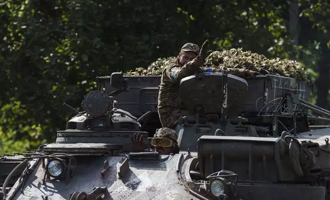 Ukrainian servicemen ride atop on armoured vehicle at the Russian-Ukrainian border in Sumy region, Ukraine, Wednesday, Aug. 14, 2024. (AP Photo/Evgeniy Maloletka)