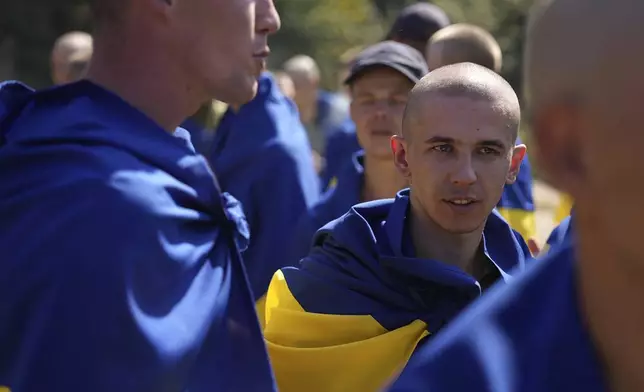 In this photo provided by the Ukrainian Presidential Press Office on Saturday, Aug. 24, 2024, Ukrainian prisoners of war are wrapped in national flags after a prisoners exchange at an undisclosed location in Ukraine. (Ukrainian Presidential Press Office via AP)