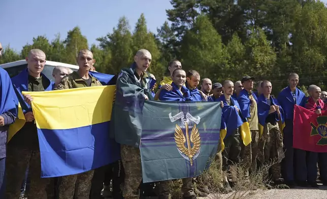 In this photo provided by the Ukrainian Presidential Press Office on Saturday, Aug. 24, 2024, Ukrainian prisoners of war hold their units flags after a prisoners exchange at an undisclosed location in Ukraine. (Ukrainian Presidential Press Office via AP)