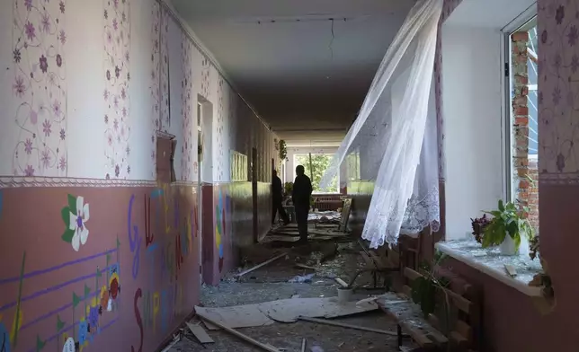 Serhii Zaichenko, 63, school guard walks in the corridor of his school which was heavily damaged after Russian airstrike in Mohrytsia, near Russian-Ukrainian border, Sumy region, Ukraine, Wednesday, Aug. 14, 2024. Zaichenko said two people were killed, including one child. (AP Photo/Evgeniy Maloletka)