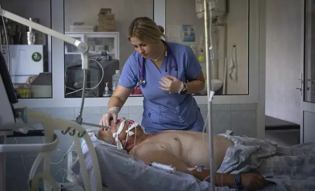 Angelina, a doctor who volunteers at night for an air-defense unit, checks on a patient in the intensive care unit at a hospital in Bucha, Kyiv region, Ukraine, Aug. 15, 2024. (AP Photo/Efrem Lukatsky)