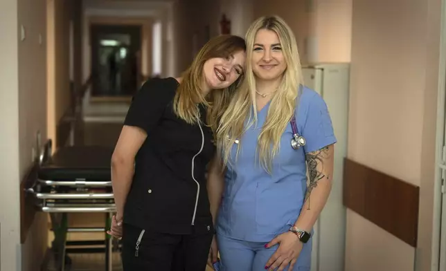 Olena, left, and Angelina, doctors who volunteer at night for an air-defense unit, pose for a photo in a hospital in Bucha, Kyiv region, Ukraine, Aug. 15, 2024. (AP Photo/Efrem Lukatsky)