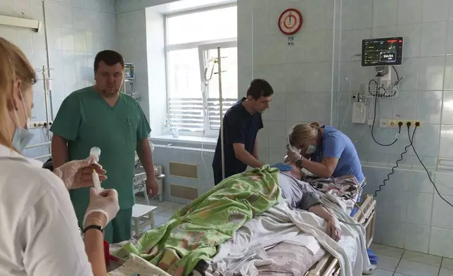 Angelina, a doctor who volunteers at night for an air-defense unit, inserts a breathing tube in a patient in a hospital in Bucha, Kyiv region, Ukraine, Aug. 15, 2024. (AP Photo/Vasilisa Stepanenko)