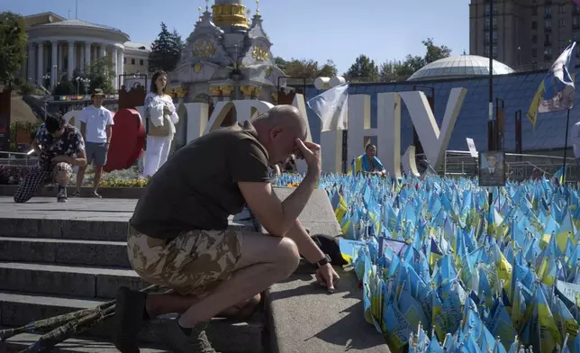 A veteran pays his respect at a makeshift memorial for fallen Ukrainian soldiers in the Russian-Ukrainian war during Ukrainian Independence Day on Independence Square in Kyiv, Ukraine, Saturday, Aug. 24, 2024. (AP Photo/Efrem Lukatsky)