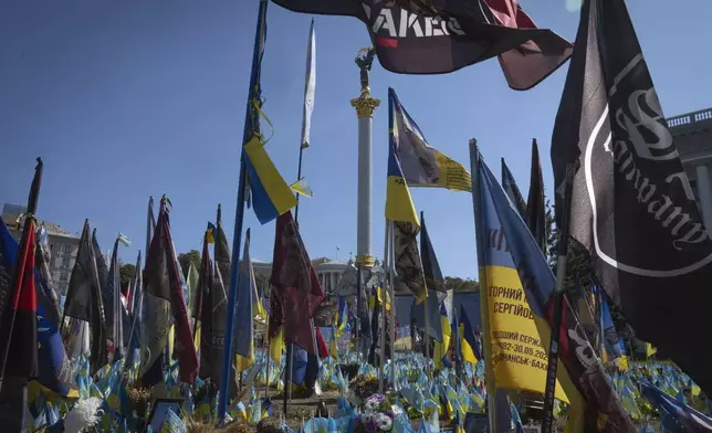 Flags with the names of killed soldiers are carried at a makeshift memorial for fallen Ukrainian soldiers in the Russian-Ukrainian war during Ukrainian Independence Day on Independence Square in Kyiv, Ukraine, Saturday, Aug. 24, 2024. (AP Photo/Efrem Lukatsky)