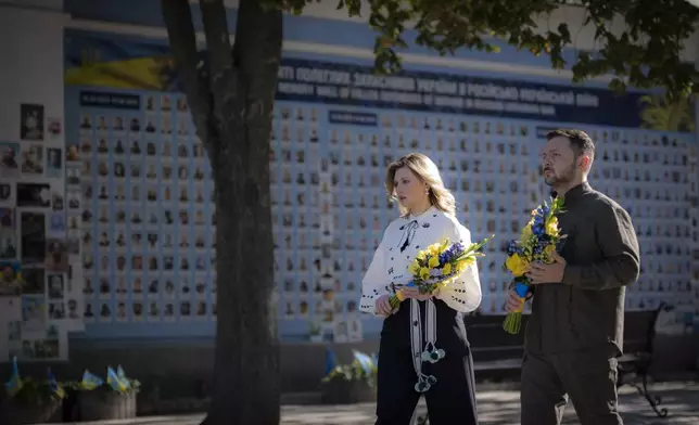 In this photo provided by the Ukrainian Presidential Press Office, Ukrainian President Volodymyr Zelenskyy and his wife Olena lay flowers at the Memorial Wall of Fallen Defenders of Ukraine in Russian-Ukrainian War during celebration of the Ukrainian Independence Day in Kyiv, Ukraine, Saturday, Aug. 24, 2024. (Ukrainian Presidential Press Office via AP)