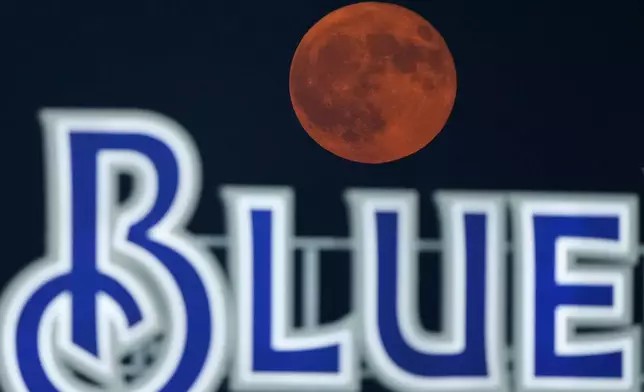 The supermoon rises above a beer sign during a baseball game between the Kansas City Royals and the Los Angeles Angels, Monday, Aug. 19, 2024, in Kansas City, Mo. (AP Photo/Charlie Riedel)