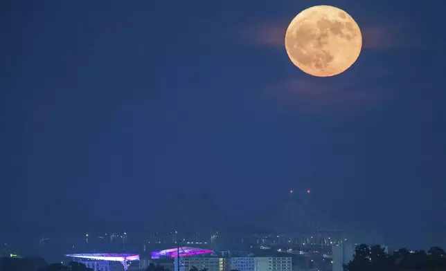 A blue supermoon rises over the Crescent City Connection bridge in New Orleans, Monday, Aug. 19, 2024. (David Grunfeld/The Times-Picayune/The New Orleans Advocate via AP)