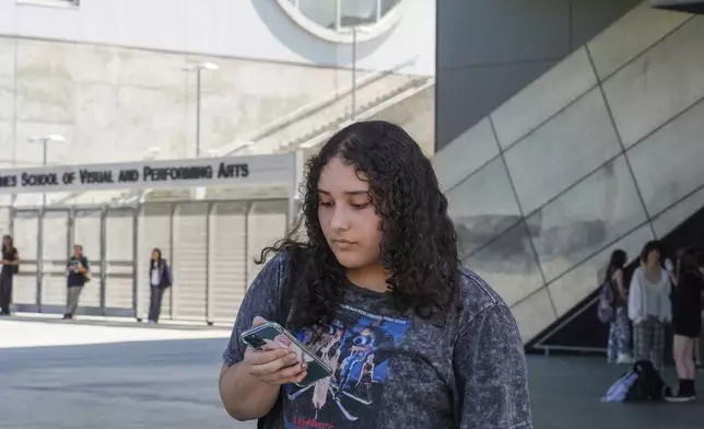 Student April Yamilet, 17, uses her cellphone as she steps outside the Ramon C. Cortines School of Visual and Performing Arts High School in downtown Los Angeles on Tuesday, Aug. 13, 2024. (AP Photo/Damian Dovarganes)