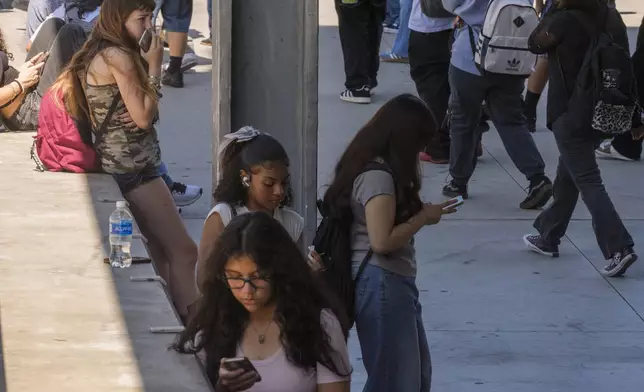 Students use their cellphones as they leave for the day the Ramon C. Cortines School of Visual and Performing Arts High School in downtown Los Angeles on Tuesday, Aug. 13, 2024. (AP Photo/Damian Dovarganes)