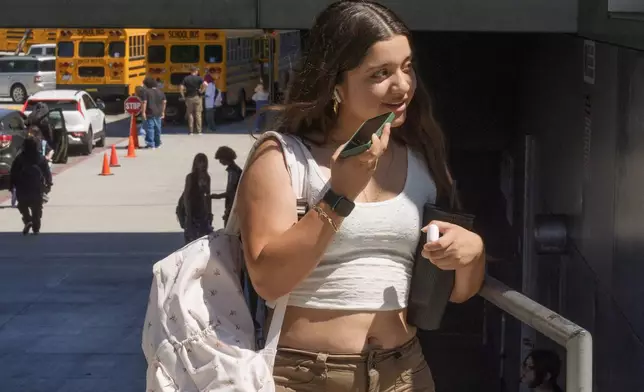 Student Maybelline Herrera uses her cellphone as she steps outside the Ramon C. Cortines School of Visual and Performing Arts High School in downtown Los Angeles on Tuesday, Aug. 13, 2024. (AP Photo/Damian Dovarganes)