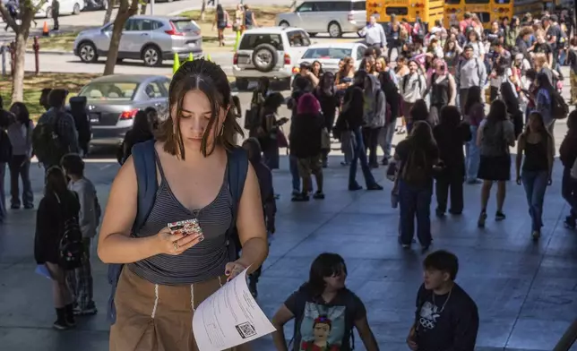 Student Keiran George uses her cellphone as she steps outside the Ramon C. Cortines School of Visual and Performing Arts High School in downtown Los Angeles on Tuesday, Aug. 13, 2024. (AP Photo/Damian Dovarganes)