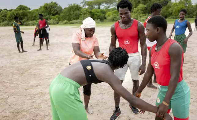 Coach Isabelle Sambou, 43 years old, two-time Olympian and nine-time African wrestling champion, left, speaks to young women during a wrestling training in Mlomp, southern Senegal, Wednesday, July 10, 2024. (AP Photo/Sylvain Cherkaoui)