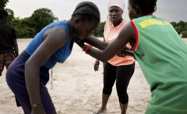 Coach Isabelle Sambou, 43 years old, two-time Olympian and nine-time African wrestling champion, center, explains moves to young women during a wrestling training, in Mlomp, southern Senegal, Wednesday, July 10, 2024. AP Photo/Sylvain Cherkaoui)