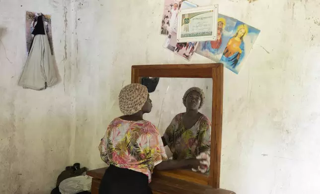 Coach Isabelle Sambou, 43 years old, two-time Olympian and nine-time African wrestling champion, cleans a mirror inside her room in Mlomp, southern Senegal, Wednesday, July 10, 2024. (AP Photo/Sylvain Cherkaoui)