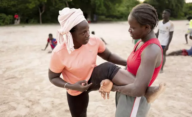 Coach Isabelle Sambou, 43 years old, two-time Olympian and nine-time African wrestling champion, left, explains a move during a wrestling training in Mlomp, southern Senegal, Wednesday, July 10, 2024. (AP Photo/Sylvain Cherkaoui)