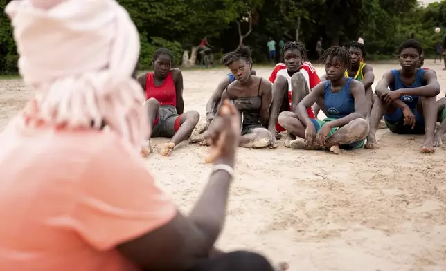 Coach Isabelle Sambou, 43 years old, two-time Olympian and nine-time African wrestling champion, back to camera, speaks to young women before a wrestling training in Mlomp, southern Senegal, Wednesday, July 10, 2024. (AP Photo/Sylvain Cherkaoui)