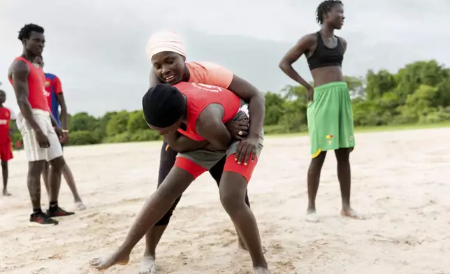 Coach Isabelle Sambou, 43 years old, rear, two-time Olympian and nine-time African wrestling champion, explains a move to a young woman during a wrestling training in Mlomp, southern Senegal, Wednesday, July 10, 2024. (AP Photo/Sylvain Cherkaoui)