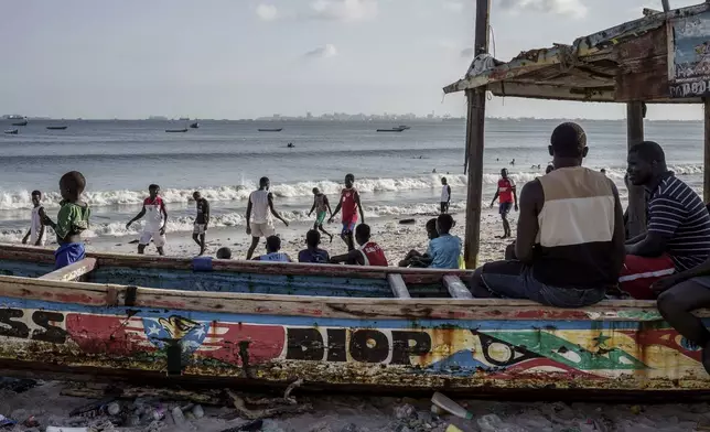 People lounge at the beach in Thiaroye-Sur-Mer, Senegal, Friday, Aug. 23, 2024. Migrants leave on artisanal fishing boats known as pirogues and navigate for several days against strong winds and Atlantic currents. While thousands have survived the risky journey, many die or disappear along the way with remains sometimes washing up on the other side of the Atlantic. (AP Photo/Annika Hammerschlag)