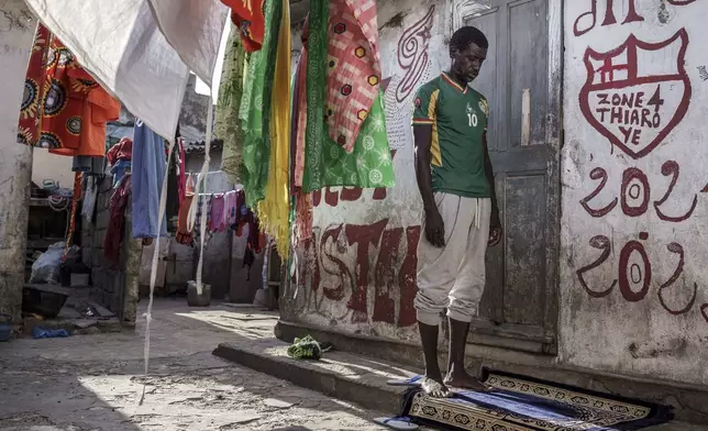 Cheikh Gueye, a 46-year-old fisherman who recently tried to migrate to Europe, prays at his family house in Thiaroye-Sur-Mer, Senegal, Friday, Aug. 23, 2024. Migrants leave on artisanal fishing boats known as pirogues and navigate for several days against strong winds and Atlantic currents. While thousands have survived the risky journey, many die or disappear along the way with remains sometimes washing up on the other side of the Atlantic. (AP Photo/Annika Hammerschlag)