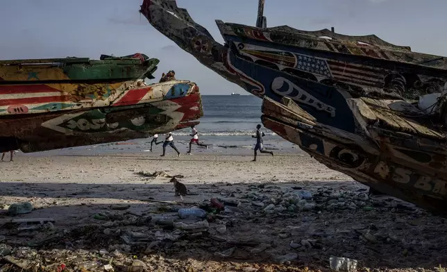 Youths play soccer on the beach in Thiaroye-Sur-Mer, Senegal, Friday, Aug. 23, 2024. Migrants leave on artisanal fishing boats known as pirogues and navigate for several days against strong winds and Atlantic currents. While thousands have survived the risky journey, many die or disappear along the way with remains sometimes washing up on the other side of the Atlantic. (AP Photo/Annika Hammerschlag)