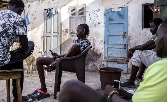 Salamba Ndeye, center, a 28-year-old who tried to migrate to Europe twice, is photographed in her family house in Thiaroye-Sur-Mer, Senegal, Friday, Aug. 23, 2024. Salamba is one of thousands of young Senegalese who try to flee poverty and the lack of job opportunities in the West African country each year to head to Spain. More than 22,300 people have landed on the Canary Islands from January to mid-August this year. (AP Photo/Annika Hammerschlag)