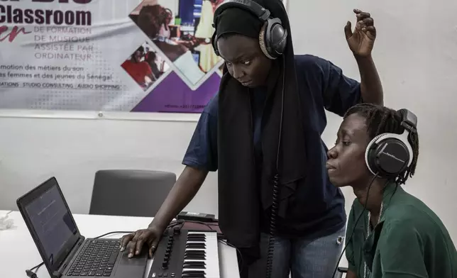 Aminata "Myamy TheAyGirl" Thiam, 31years - Old, left, instructs a student 30 years old Julia Sall, at a beat making class for women in Dakar, Senegal, Wednesday, Aug. 14, 2024. Aminata Thiam is Senegal's first female beatmaker. (AP Photo/Annika Hammerschlag)