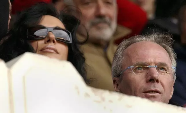 FILE _ England soccer team coach Sven Goran Eriksson, right, and his partner Nancy get ready for the start of the English Premiership soccer match between Arsenal and Manchester United, played at Highbury stadium in London, Sunday March 28, 2004. Eriksson the Swedish soccer manager who spent five years as England’s first ever foreign-born coach, has died. He was 76, it was announced on Monday, Aug. 26, 2024.(AP Photo/Richard Lewis, File)