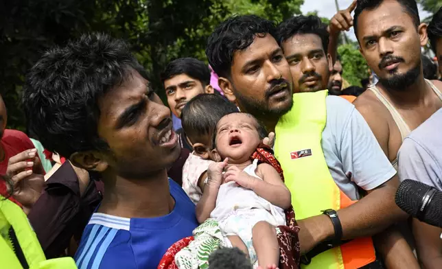 Volunteers rescue a ten-day-old child and her mother from flooded areas in Feni, a coastal district in southeast Bangladesh, Friday, Aug. 23, 2024. (AP Photo/Fatima Tuj Johora)