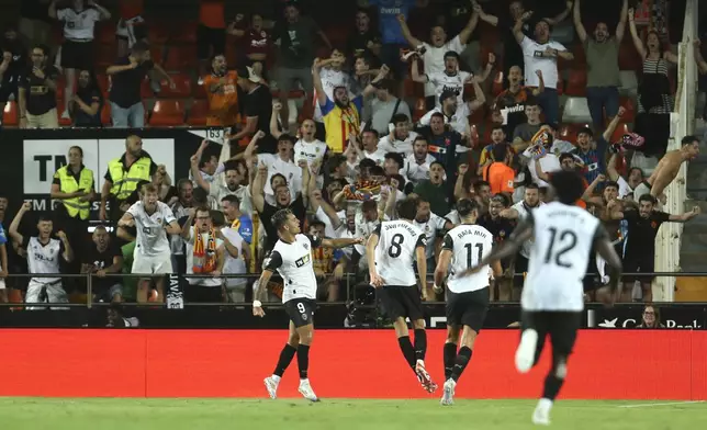 Valencia's Hugo Duro, centre, celebrates after scoring the opening goal during the Spanish La Liga soccer match between Valencia and FC Barcelona at the Mestalla stadium in Valencia, Spain, Saturday, Aug. 17, 2024. (AP Photo/Alberto Saiz)