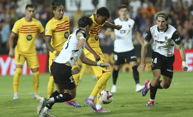 Barcelona's Lamine Yamal, centre, and Valencia's Jesus Vazquez, centre left, challenge for the ball during the Spanish La Liga soccer match between Valencia and FC Barcelona at the Mestalla stadium in Valencia, Spain, Saturday, Aug. 17, 2024. (AP Photo/Alberto Saiz)